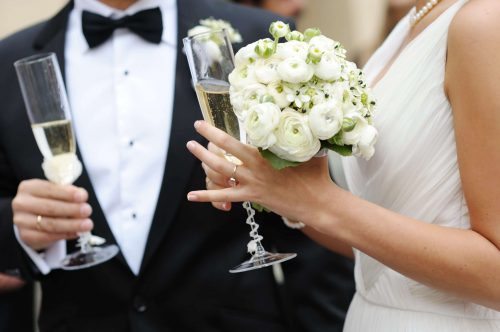 Bride and groom are holding champagne glasses